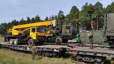 Автокран и военные грузовики на платформах, военнослужащие у состава