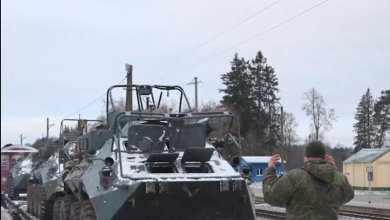 Бронетранспортёр на платформе и военнослужащий у состава на станции зимой