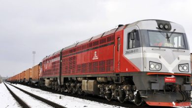 Грузовой тепловоз в красно-белой окраске с составом зимой
