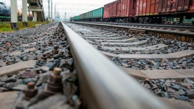 Рельс крупным планом, на соседних путях грузовые составы