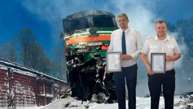 Двое железнодорожников с грамотами на фоне разбитого тепловоза