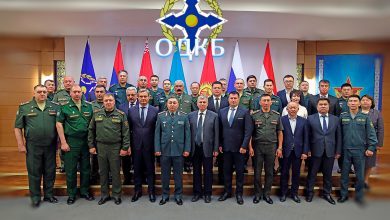 Групповой снимок военных и гражданских участников на фоне эмблемы и флагов ОДКБ