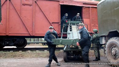 Люди выгружают ящики из крытого вагона в грузовик, надпись «Фото носит иллюстративный характер»