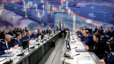 Участники совещания за длинным столом на фоне биржевого графика