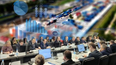 Участники итогового совещания за столами, на фоне инфографика