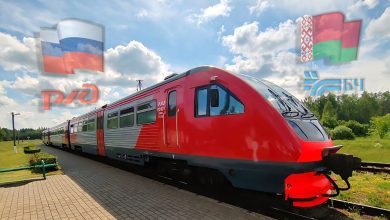 Рельсовый автобус в красной окраске у платформы, флаги и логотипы РЖД и БЧ