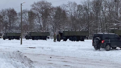 Военные грузовики и внедорожник на заснеженной площадке у станции