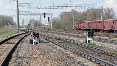 Станционные пути со светофорами, крытые вагоны на соседнем пути