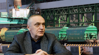 Мужчина в пиджаке на фоне вагонов-хопперов у погрузочного узла
