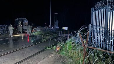 Пограничный переход ночью: закрытые ворота, колючая проволока, военнослужащие и машина у путей