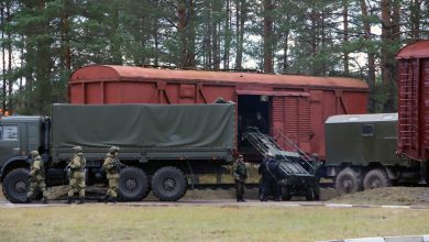 Военнослужащие и армейские грузовики у крытых вагонов