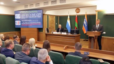 Совещание в зале: выступающий за трибуной, на экране слайд, в зале участники