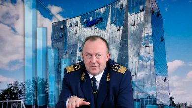Мужчина в форме железнодорожника на фоне стеклянного здания с логотипом БЖД