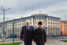 Двое мужчин в пальто на площади перед административным зданием