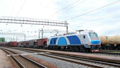 Грузовой электровоз в бело-синей окраске с составом на станционных путях