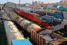 Полувагоны и цистерны на станционных путях, контур карты Украины со стрелкой