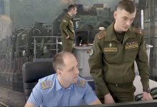 Диспетчер в форме железнодорожника и военнослужащий у пульта управления движением